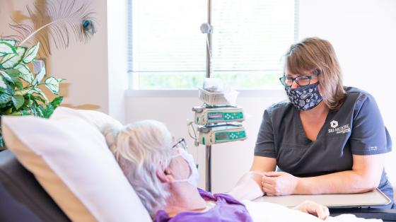 Nurse watching over a patient who is laying in a hospital bed