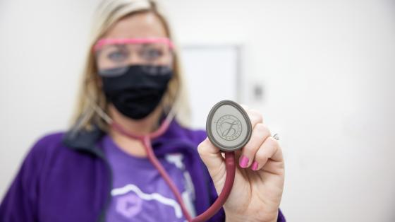 Nurse wearing personal protective equipment holding a stethoscope