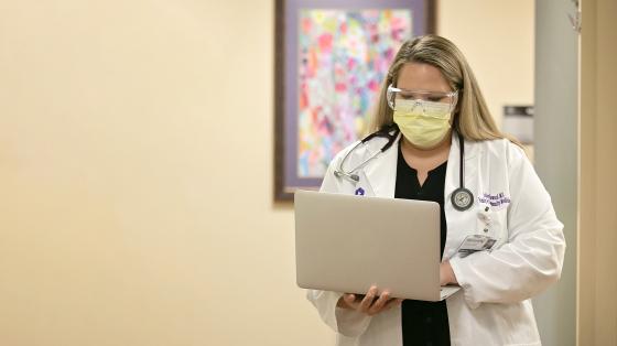 Doctor walking with an open laptop computer